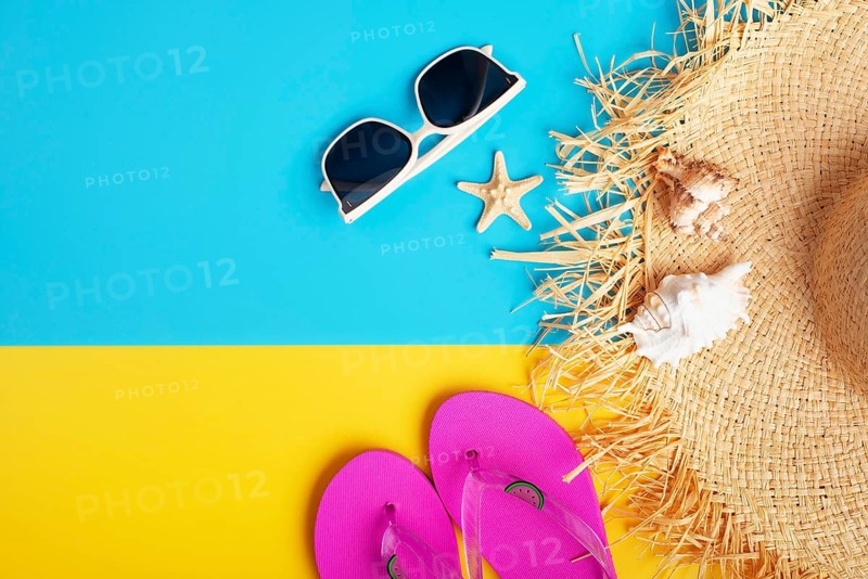 Straw hat sunglesses flip flops and shells on yellow and blue background vacation travel planning mockup