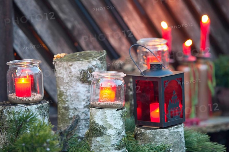 Red candles in glasses and a lantern stand on wood with green branches, borken, münsterland, germany