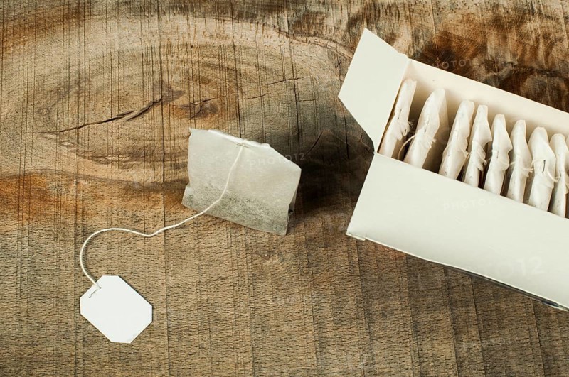 Box with tea bags on wood. Tea bag with label