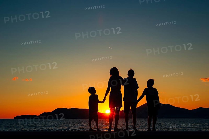Silhouette of a family with children against the backdrop of the setting sun and sea in Montenegro