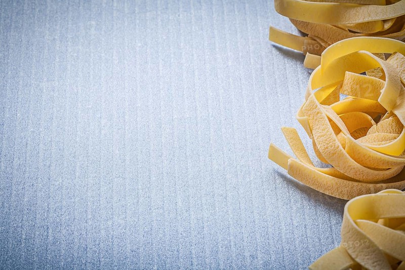 Copy space of rolled pasta fettuccine on blue background food and drink concept