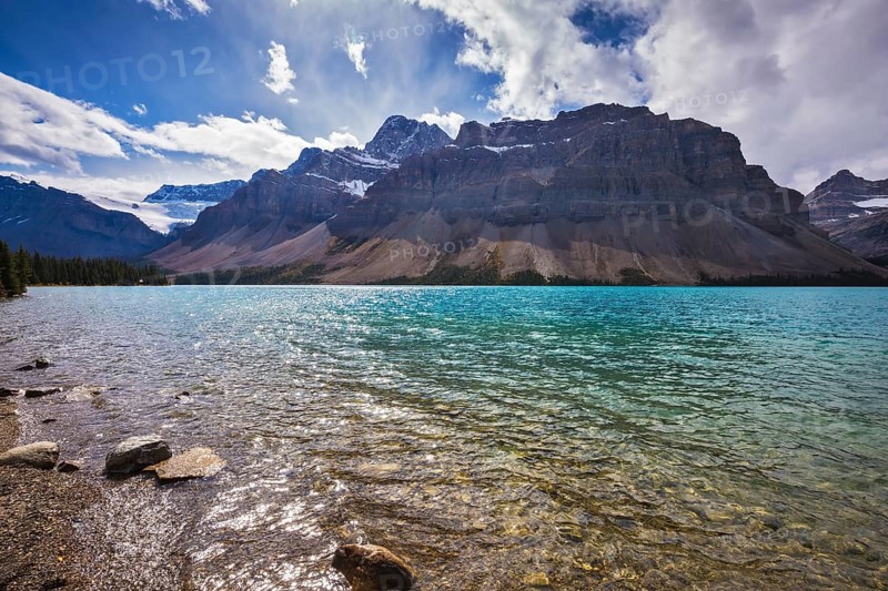 The cold waters of the lake surrounded by scenic Canadian Rocky Mountains. Azure Bow Lake in Banff National Park