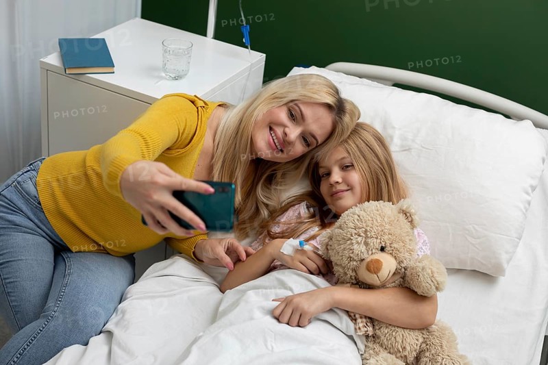 A heartwarming selfie captures a loving mother and daughter sharing a joyful moment in a hopeful hospital room