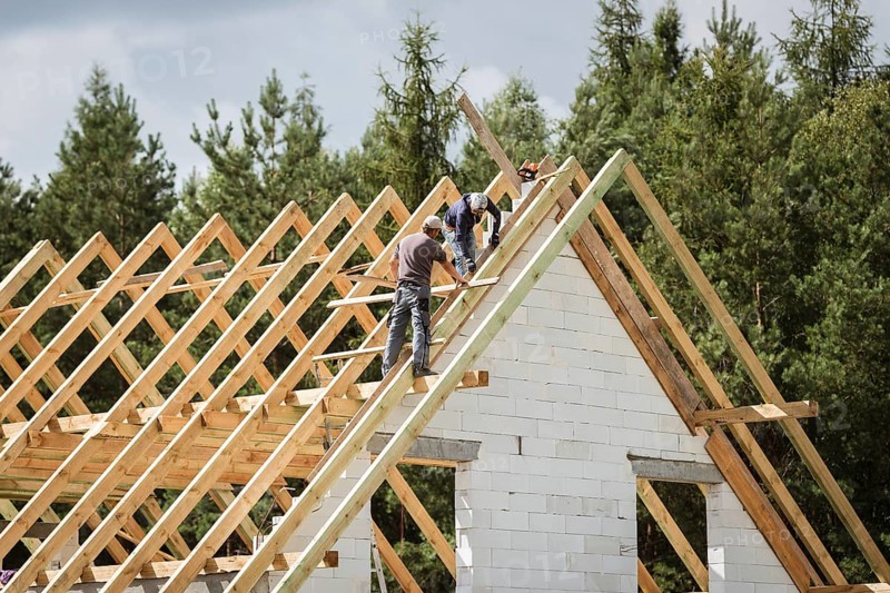 Two men work on the roof of house construction
