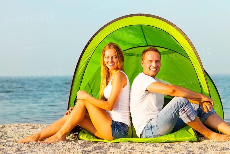 Happy young couple camping on the beach. Summertime