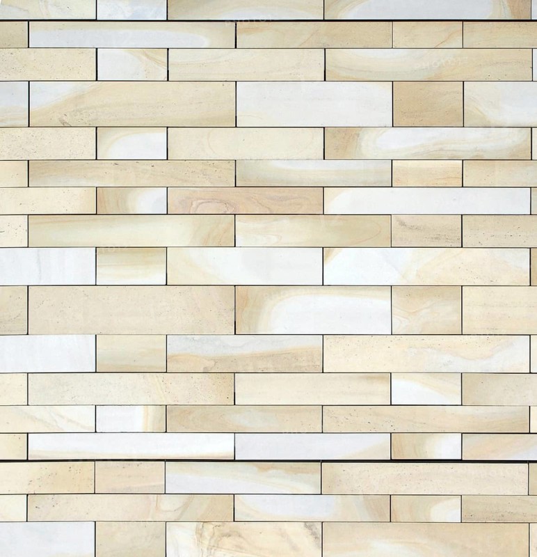 Full frame image of a wall made of large flat blocks of textured yellow light brown york stone in different sized rows