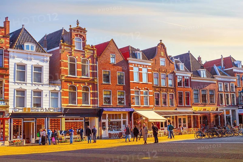 Delft, Netherlands, April 8, 2016: Colorful street view with cheese shop, houses and people