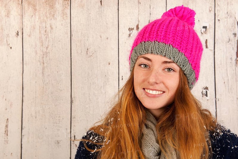 Portrait girl with pink winter hat in front of wooden background