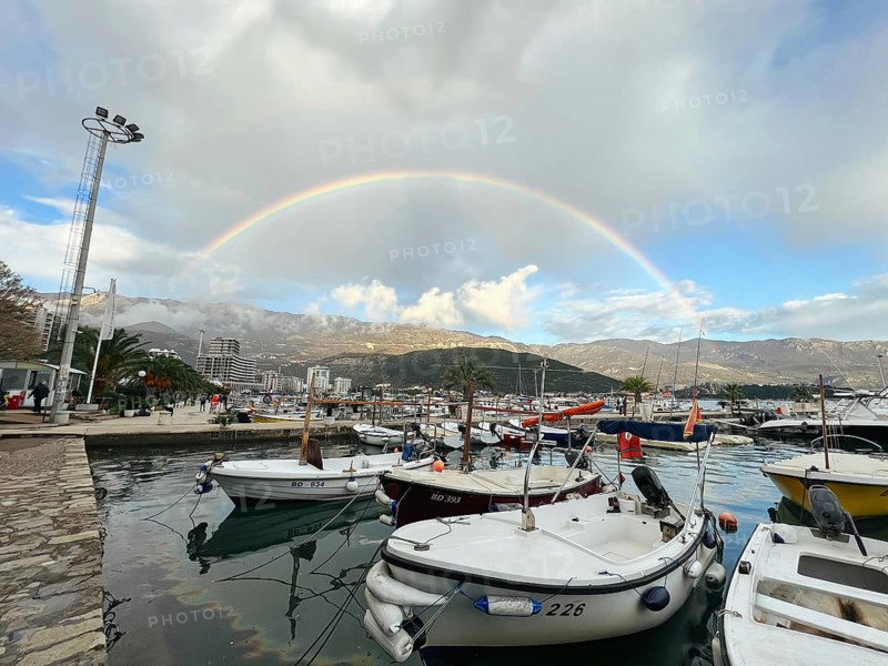 Yachts moored at the pier against the backdrop of a rainbow over the mountains.
