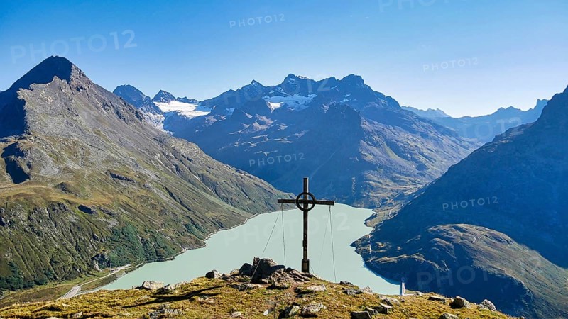 Summit cross on the Bielerkof with views of the Silvretta reservoir, Hohes Rad, Piz Buin and other peaks