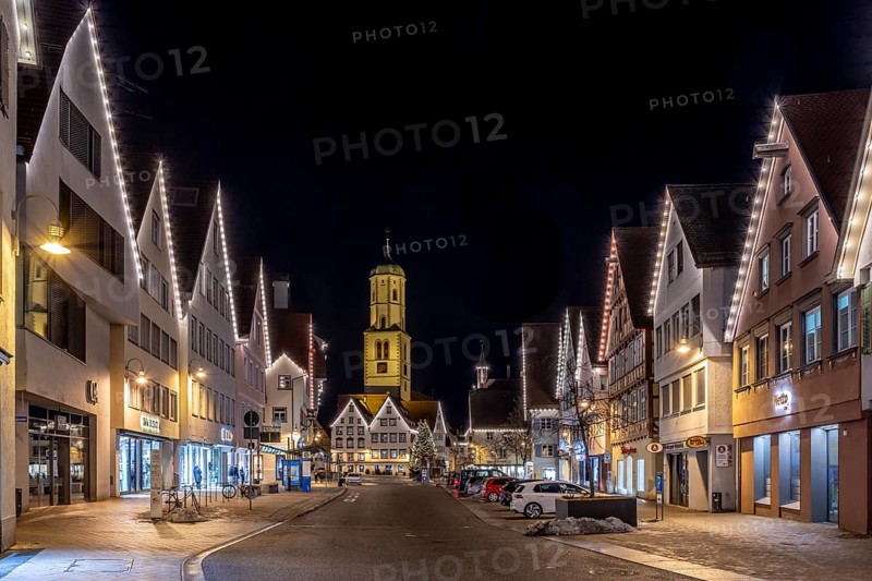 Night photo of historic buildings around the market square with Christmas tree and Christmas lights around the roofs of the buildings and in the background the steeple of the parish church of St Martin, Biberach an der Riß, Upper Swabia, Baden-Württemberg, Germany, Europe