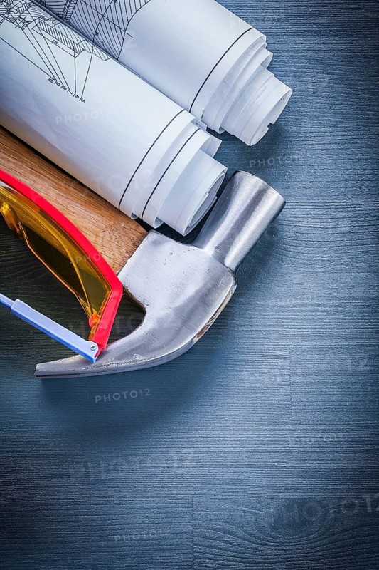 Vertical view rolled up blueprints hammer goggles
