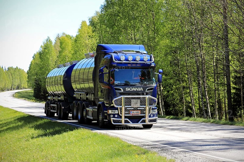 TENHOLA, FINLAND, JUNE 4, 2017: Dark blue Scania R580 tank truck with bull bar of Tomppa Tuomisto Ky moves along highway in light and shadow of a rural landscape in South of Finland at summer