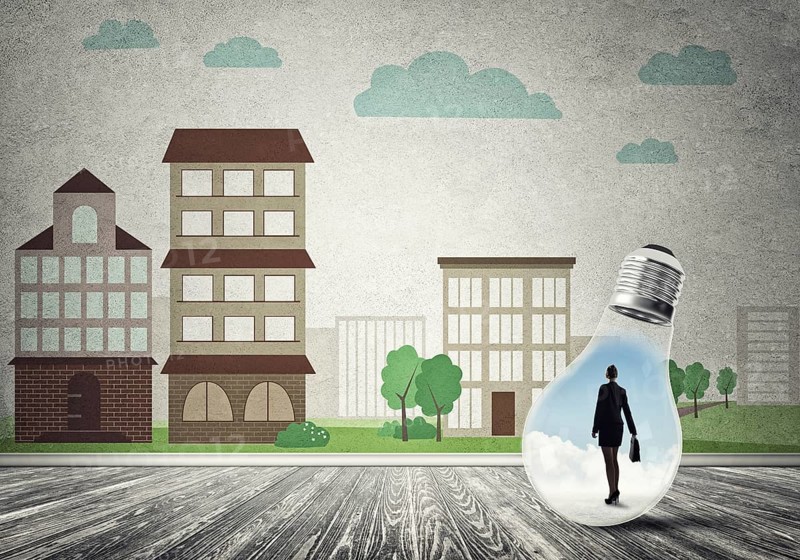 Businesswoman inside light bulb against city drawn concept