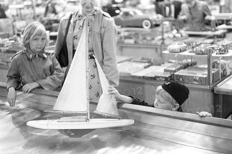 Toys in the 1950s. At a department store a boy is curious of the nice sailboat model floating in the water and touches it. Sweden 1954 Kristoffersson ref 2A-33