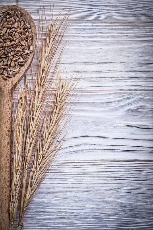 Wheat-rye ears wooden spoon grain on wood board