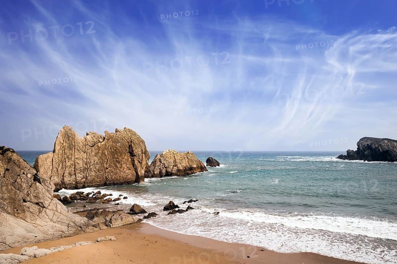Snow-white sea foam glistens in the dim autumn sun. Cantabria, Spain. Playa de la Arnia beach. Amazing geological formations amaze tourists. Storm waves break on the coastal rocks
