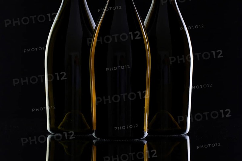Three different bottles of wine on the black glass