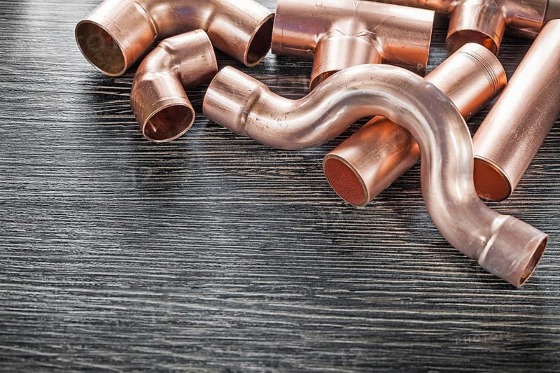 Plumbing copper water pipe fittings on wooden board