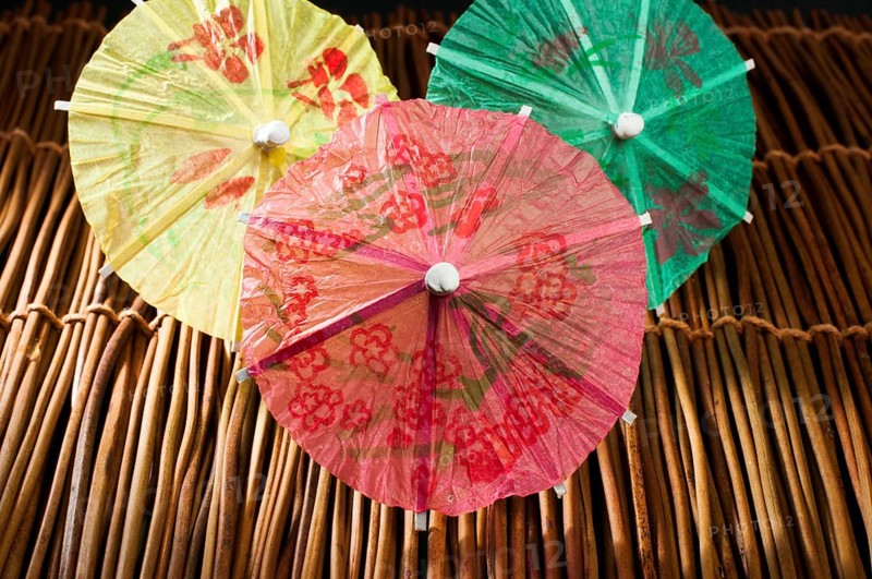 Colorful cocktail umbrellas on wooden base. Close up