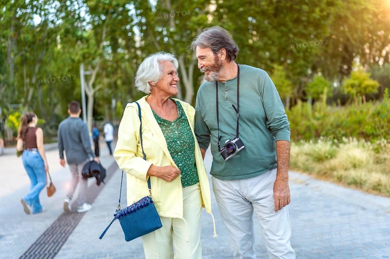 Three quarter length photo of a caucasian cute senior couple walking together along a city park
