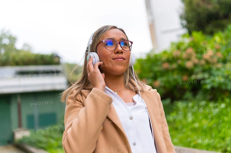 Latin woman listening to music walking along the street in a residential area