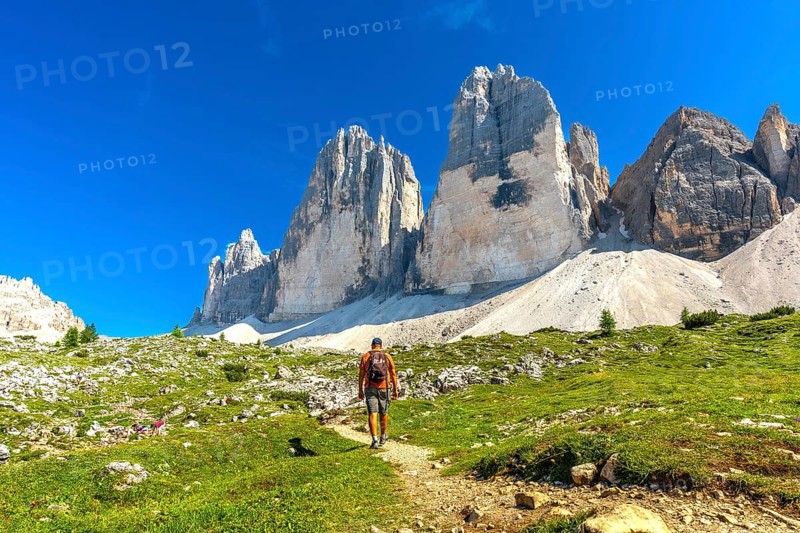 Tourist enjoying a summer hike on a scenic trail leading to the majestic tre cime di lavaredo peaks in the dolomites, italy