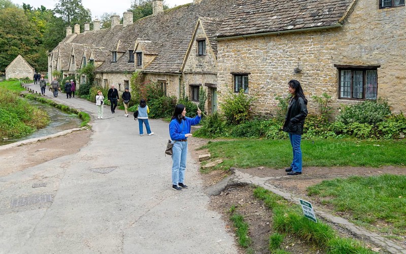 Tourists visiting famous Cotswold buildings at Arlington Row, Bibury, Gloucestershire, England, UK