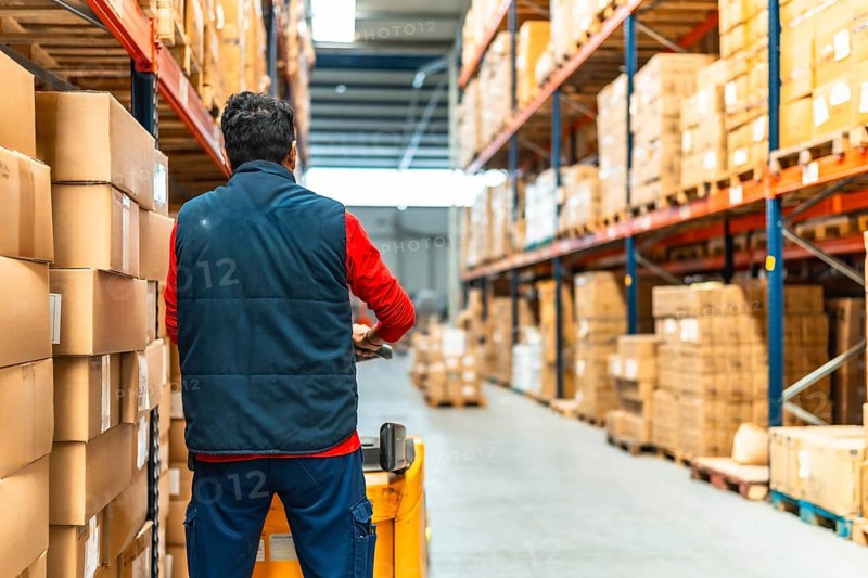 Rear view of a latin worker with machinery in the logistics warehouse