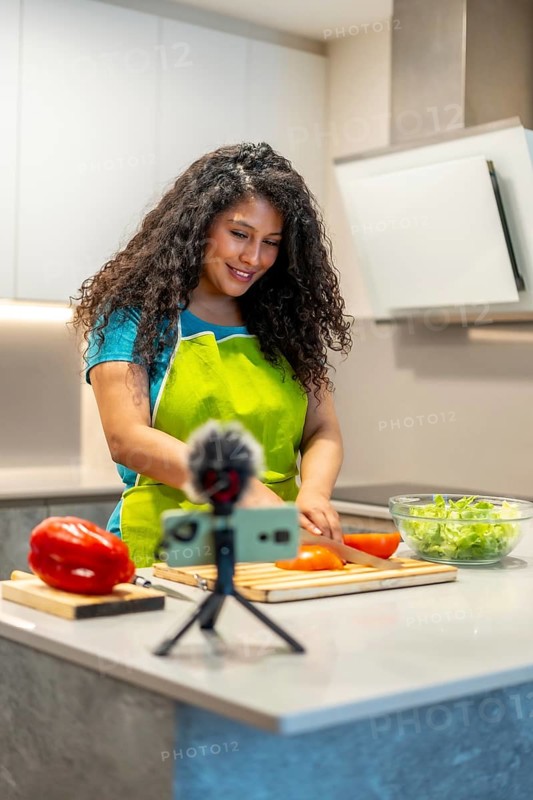Vertical photo of a latin young female influencer recording a health food tutorial at home