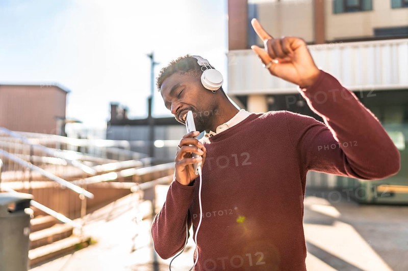 African man dancing listening to music with headphones in the city in a sunny day of autumn