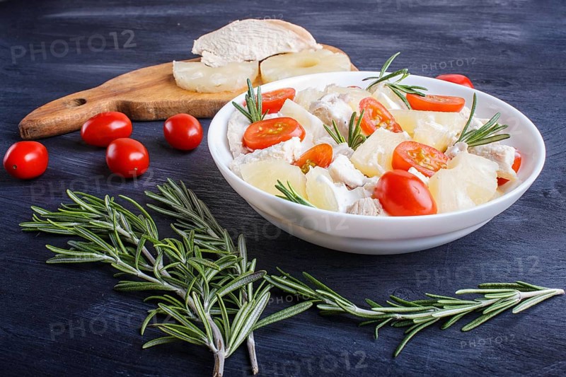Chicken fillet salad with rosemary, pineapple and cherry tomatoes on dark blue wooden background. close up, copy space