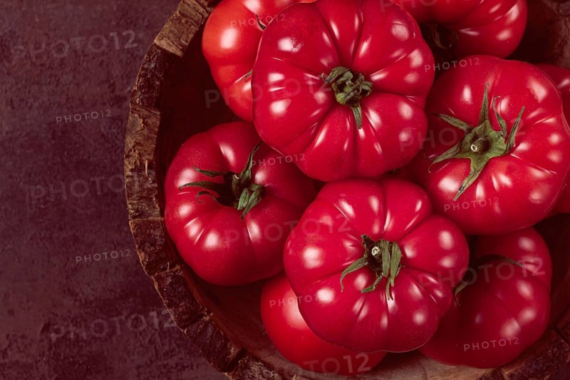 Pink tomatoes, in a rustic wooden bowl, close-up, no people