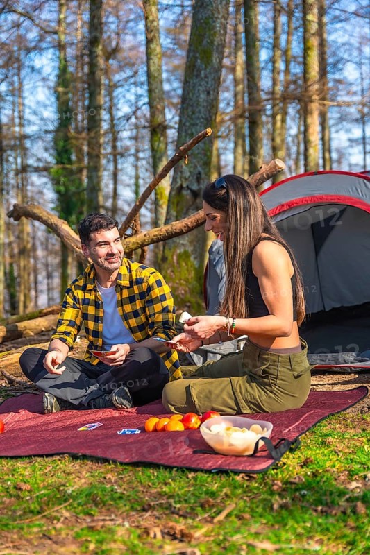 Hikers enjoying a game of cards while camping in the forest, sharing laughter and creating memories in the beauty of nature