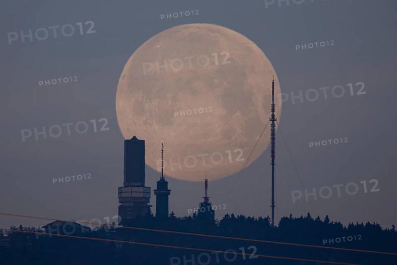 The first full moon of the year, also known as the wolf moon, disappears behind the Großer Feldberg im Taunus, Schmitten, Großer Feldberg im Taunus, Hesse, Germany, Europe