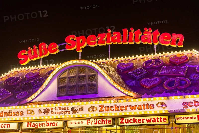 Candy stall flooded with light at a funfair at night, decorated with traditional treats, Cannstatter Wasen, folk festival, Bad Cannstatt, Stuttgart, Baden-Württemberg, Germany, Europe