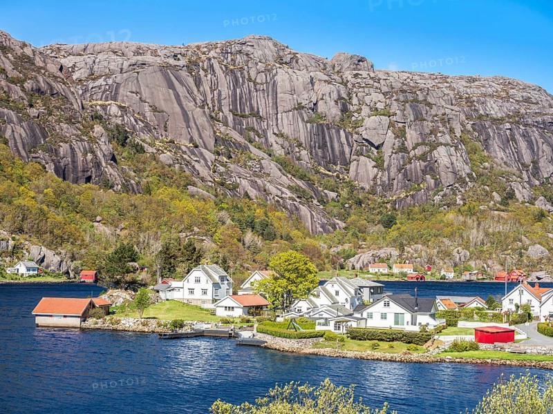 Steep granite mountains at the sea near Ana Sira, village Stornes, typcial coastal village, at coastal road 44 between Kristiansand and Egersund, southern Norway