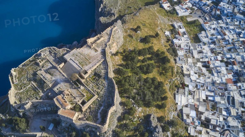 Drone shot, Acropolis of Lindos, late afternoon light, aerial view of an ancient fortress on the coast next to a white town of houses, archaeological site, Lindos, Rhodes, Dodecanese, Greek Islands, Greece, Europe