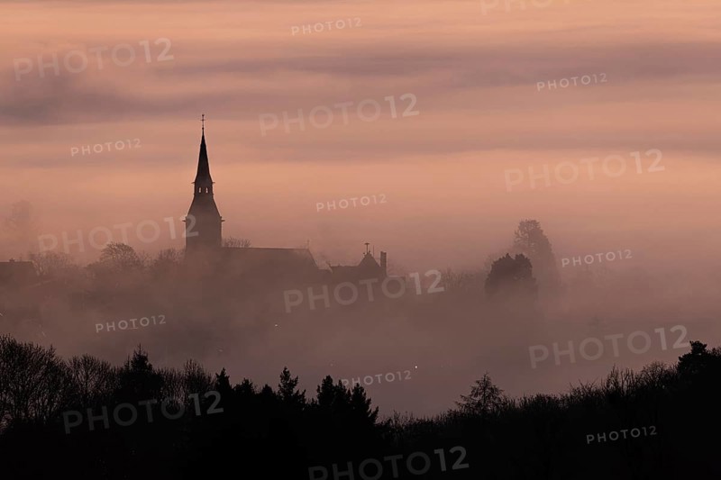 Wisps of mist drift into the town of Kronberg im Taunus in the morning shortly in front of sunrise. Only the spire of St Peter and Paul's Church stands out. Kronberg, Malerblick, Hesse, Germany, Europe
