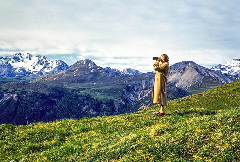 Woman standing on hillside using binoculars in mountains of national park, Western Rhaetian Alps, Switzerland, Europe 1959, Europe