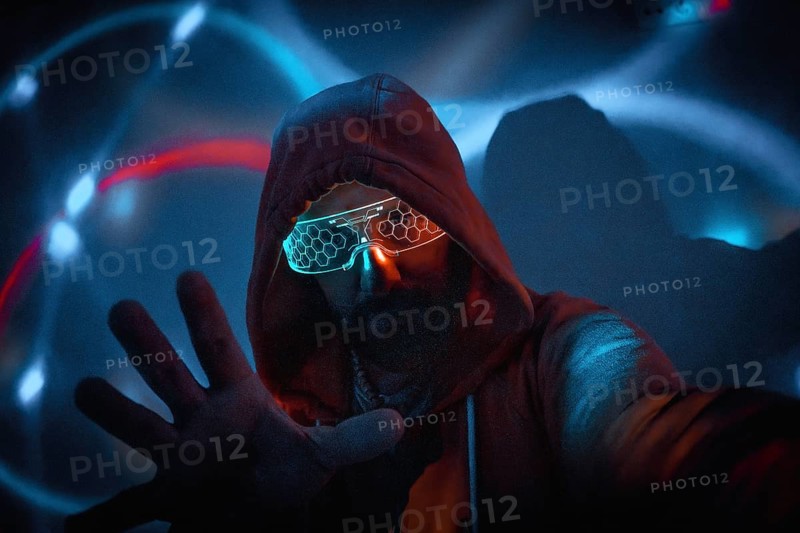 Cyberpunk man with glowing glasses uses augmented reality in futuristic technological environment