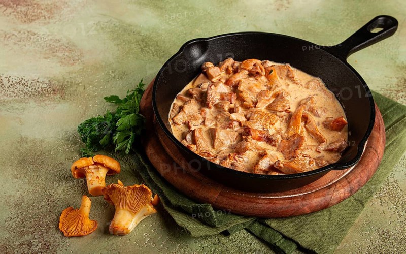 Fried chanterelle mushrooms, in cream sauce, in a cast-iron pan, homemade, no people
