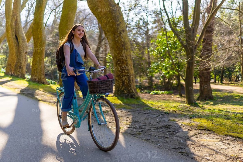 Young woman riding a vintage bicycle through a sunlit park, enjoying the fresh air and vibrant surroundings while embracing leisure and freedom