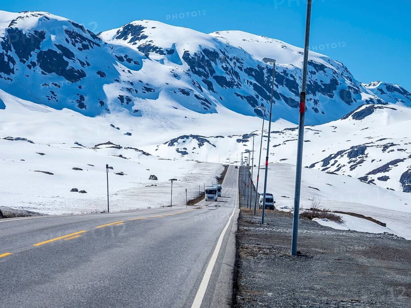 Camper vans driving through snowy high mountain landscape, Haukelivegen road, E134, Norway, Europe