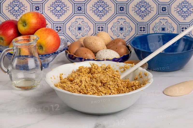 Oatmeal porridge with eggs and apples in a bowl on a marble worktop in front of patterned tiles