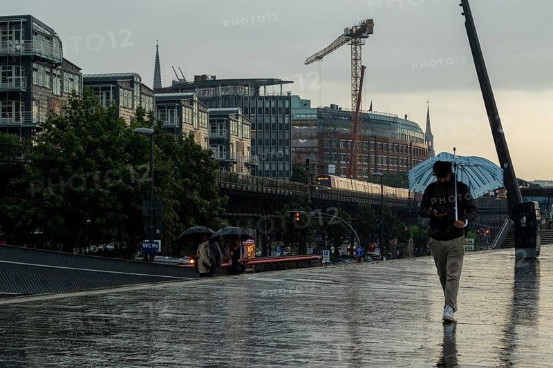 Symbolic picture weather, heavy rain in summer, thunderstorm, storm, tourist with umbrella on the way in the rain next to the underground line U3 at the Landungsbrücken in the harbour of Hamburg, Germany, Europe