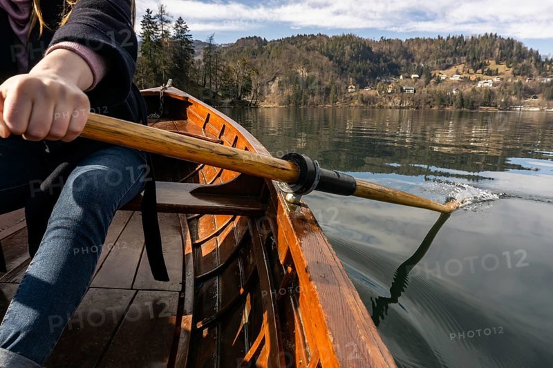 Young woman using paddle on a wooden boat, Lake Bled Slovenia rowing on wooden boats on a sunny day