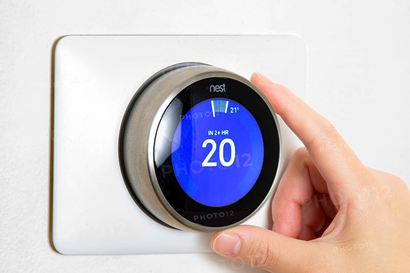 Calgary, Alberta, Canada. Jun 5, 2020. A person cooling down Home Air Conditioning, temperature is on centigrade celsius metrics using a Nest smart thermostat on a white wall