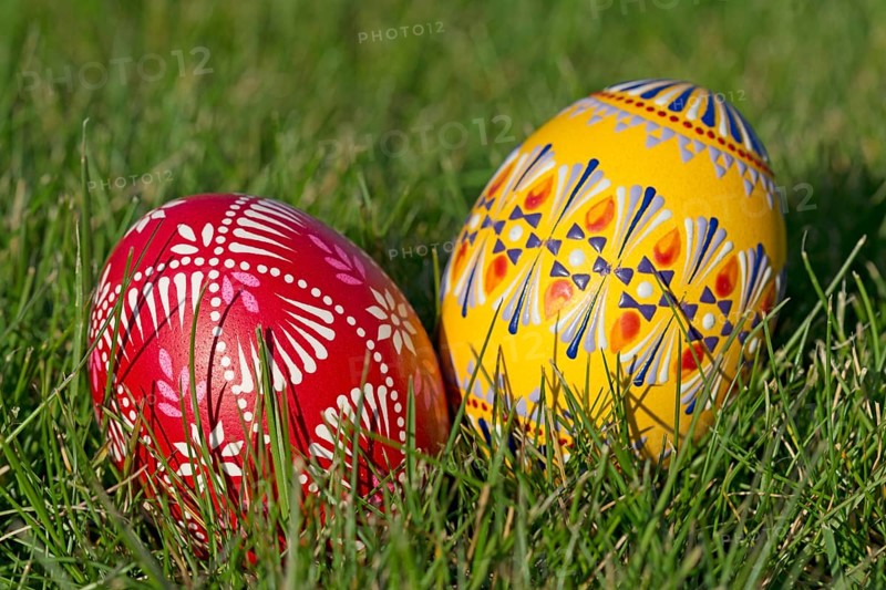 Two traditionally hand-painted Easter eggs lie in the grass