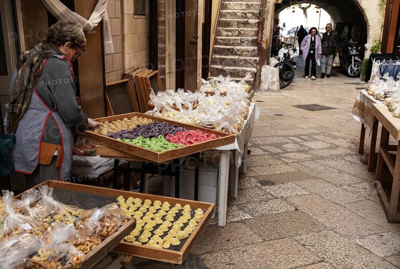 Bari, Italy, 27 November, 2023: woman pasta maker laying out her wares in the iconic Strada del Orecchiette in the old town of Bari Vecchio, Europe